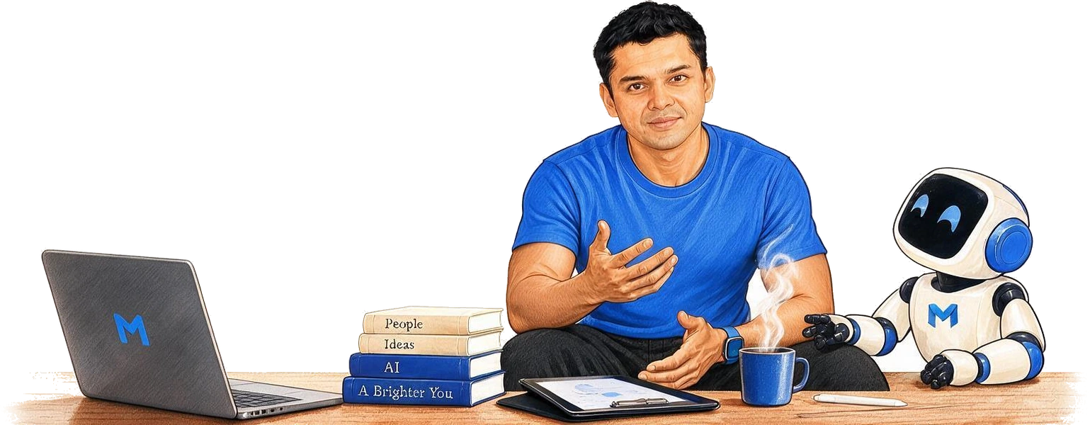 Chaithru at a desk in a Madav-blue t-shirt, one hand open mid-sentence, with an open laptop, a stack of books named People, Ideas, AI and A Brighter You, a tablet, a steaming mug, and the Madav robot sitting beside him.